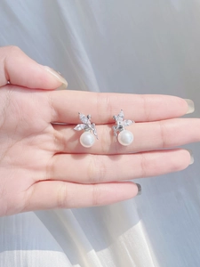Detailed macro view of S925 sterling silver pearl earrings held in hand