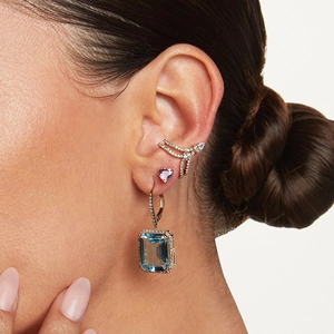Close-up of emerald-cut blue gemstone earring and heart stud with pave ear cuff