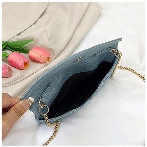 Detail view of the light blue envelope bag with gold chain strap and interior lining