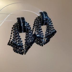 Detailed view of elegant black tassel earrings with sparkling diamond bow design