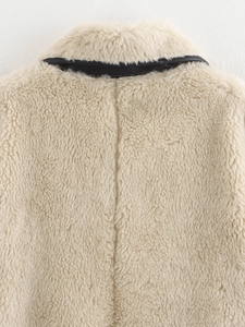 Close-up of beige faux fur coat featuring premium black leather trim and soft texture