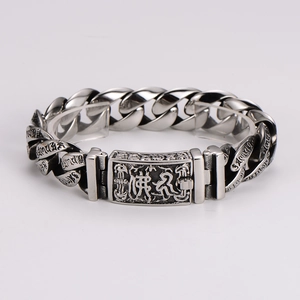 Close-up of chunky silver Cuban chain bracelet with engraved Buddhist script details