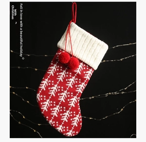Detail of red knit Christmas stocking with white tree patterns and pom-pom decorations