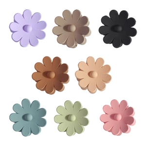 Flat lay of 8 colorful matte flower claw clips in assorted pastel shades on white background