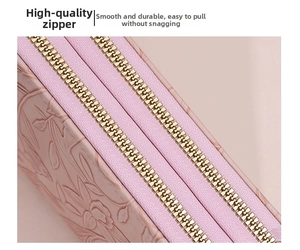 Detail of premium golden metal zipper on light pink floral embossed leather wallet
