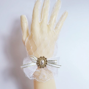 Detailed view of white lace gloves with ribbon bow, faux pearl, and rhinestone accents