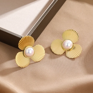 Three-petal gold textured flower stud earrings with white pearl center on satin background