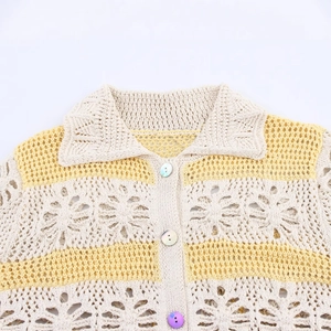 Crochet knit cardigan with floral hollow patterns and colorful pearl buttons on white background