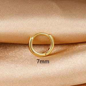 Close-up of a 7mm small golden hoop earring with polished finish on champagne silk fabric