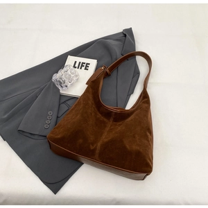 Detailed top view of a brown suede hobo bag with leather straps on a white surface