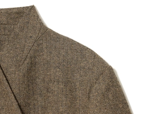 Macro shot of brown herringbone tweed fabric on jacket shoulder and collar detail