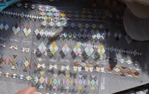 Macro shot of colorful argyle and bow pattern nail stickers with mint green tones