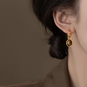 Gold-plated oval tiger eye stud earrings on model with elegant minimalist style