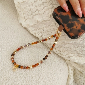 Detail der Perlen-Handykette mit bernsteinfarbenen Perlen und goldenem Herzanhänger