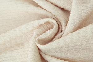 Macro detail of ivory textured crinkle fabric showing soft pleated material and weave