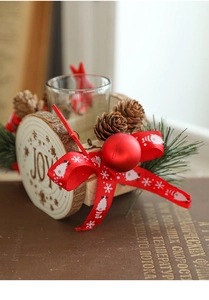 Detail of wooden Christmas candle holder with JOY lettering, pine cones, and glass cup