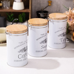 Set of 3 white coffee sugar tea canisters with bamboo lids on a kitchen counter