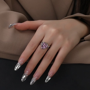 Close-up of irregular silver ring featuring a pink heart-shaped zircon on a model hand