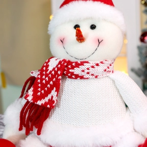 Nahaufnahme einer Schneemann-Plüschfigur mit rotem Strickschal und Weihnachtsmütze