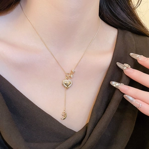 Close-up of golden heart pendant necklace with zircon inlay and moon star fringe charms