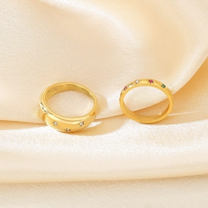 Détail de la bague dôme dorée à étoiles et de l'anneau serti de pierres colorées