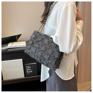 Detail of dark grey tweed shoulder bag with gold chain strap on a female model