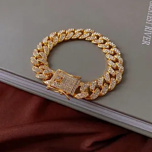 Luxurious gold-plated Cuban link necklace with sparkling crystals on a silk backdrop