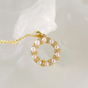 Gros plan du pendentif cœur doré avec perles et zircons sur une surface blanche