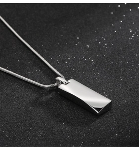 Macro shot of silver titanium pendant with snake chain on black textured surface