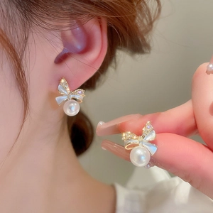 Elegant bow-knot earrings with shimmering cubic zirconia and white pearls on a model