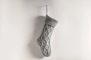 Macro detail of a grey cable knit Christmas stocking with thick ribbing and hanging loop