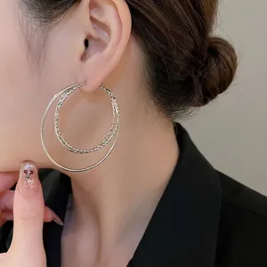 Chic silver layered hoop earrings with smooth and twisted textures on a model's ear
