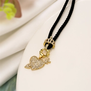 Macro shot of gold heart arrow pendant with sparkling zircon and black woven cord