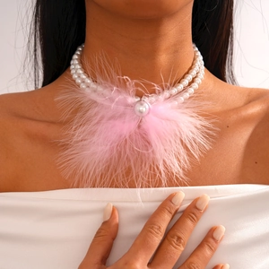 Detail of double-layer pearl necklace featuring a pink feather and large pearl pendant