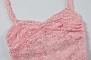 Close-up of pink floral lace fabric with delicate embroidery on a camisole dress