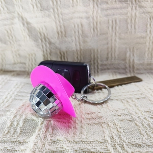Pink cowboy hat and disco ball keychain hanging on car keys with silver metal ring