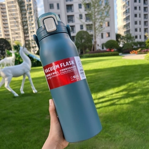 Detail of blue stainless steel vacuum flask featuring secure white locking lid and carry loop