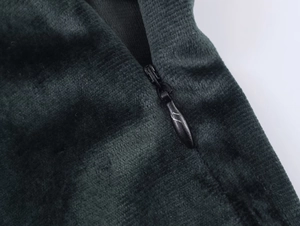 Détail de la fermeture éclair invisible sur tissu en velours vert foncé aux coutures fines