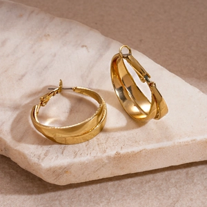 Close-up of golden geometric wide hoop earrings with double-layered metal design