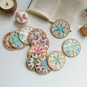 Detailed top view of handmade rattan coasters with inlaid colorful shell flower patterns