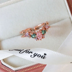 Macro shot of rose gold V-shaped ring with colorful zircon in a pink gift box