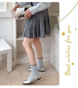 Detail of light blue ruffle socks paired with silver Mary Jane shoes and grey pleated skirt