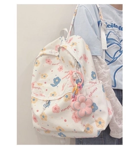 Detail of white canvas backpack with floral print and pink flower keychain pendant
