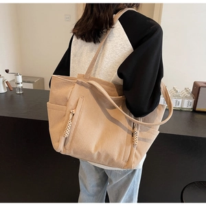 Dettaglio della borsa tote in velluto beige con tasca laterale e cerniera intrecciata