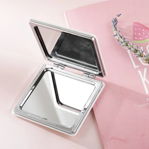 Close-up of a white portable PU leather square makeup mirror on a pink background