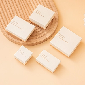 Elegant beige cardboard jewelry gift boxes in various sizes with gold lettering on a tray