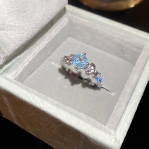 Macro detail of silver flower ring with blue zircon in a grey velvet jewelry box