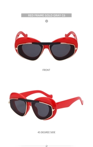 Detail view of red heart-shaped cat eye sunglasses with gold trim and grey lenses