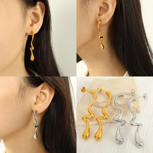 Modern wavy metal drop earrings in gold and silver finish shown on a model