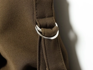 Close-up of silver metal D-rings and fabric texture on dark brown bomber jacket